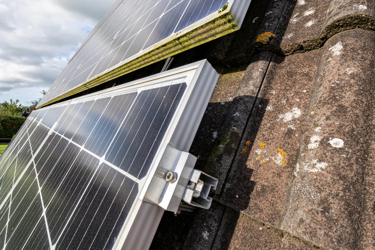 Solar panels installed along the edge of an aging roof