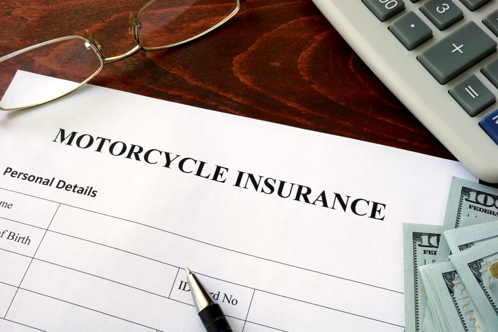 Motorcycle insurance form and dollars on the table.