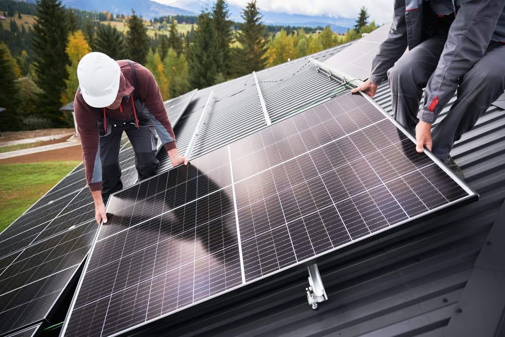 Men electricians in helmets installing solar panel system outdoors.